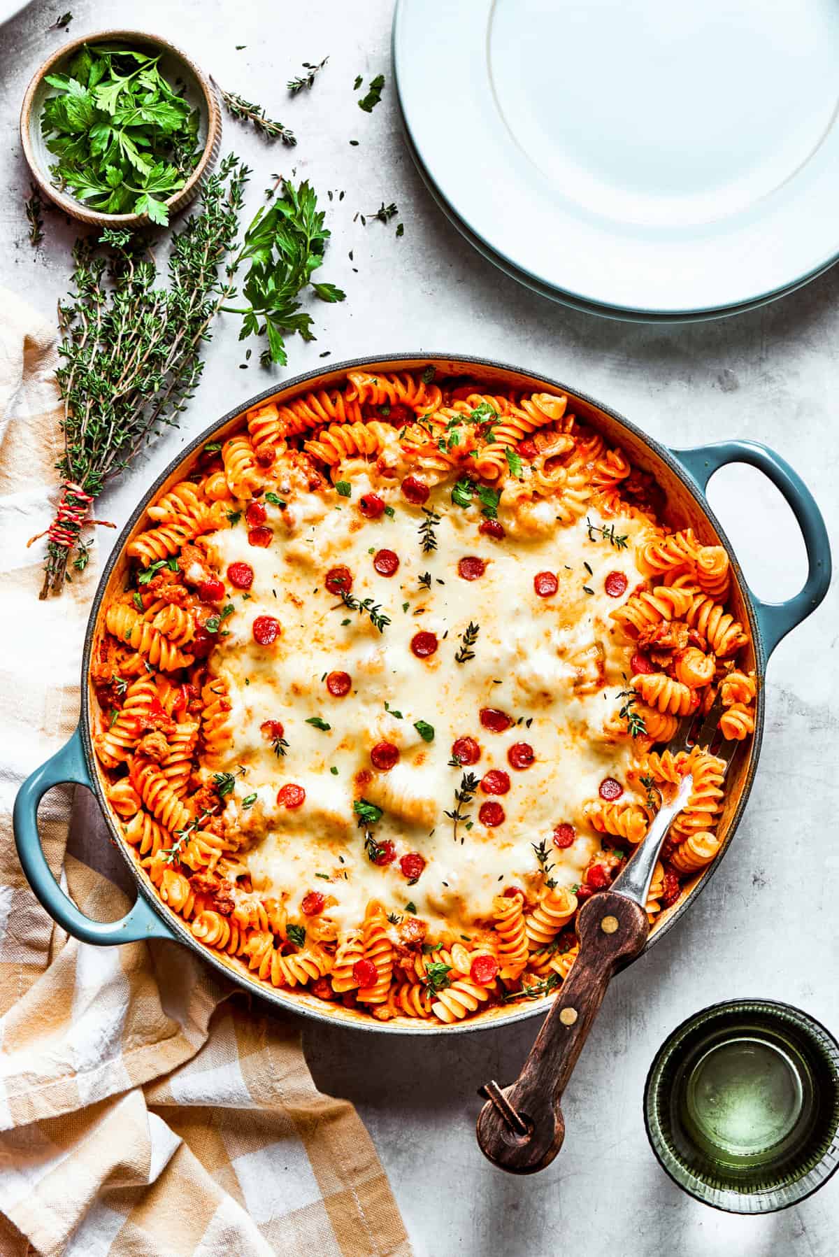 Wide shot of a baking dish with pasta topped with melted cheese and pepperoni.