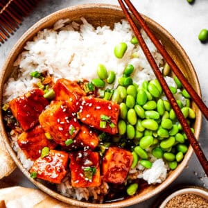 A bowl of white rice topped with cubed salmon and edamame.