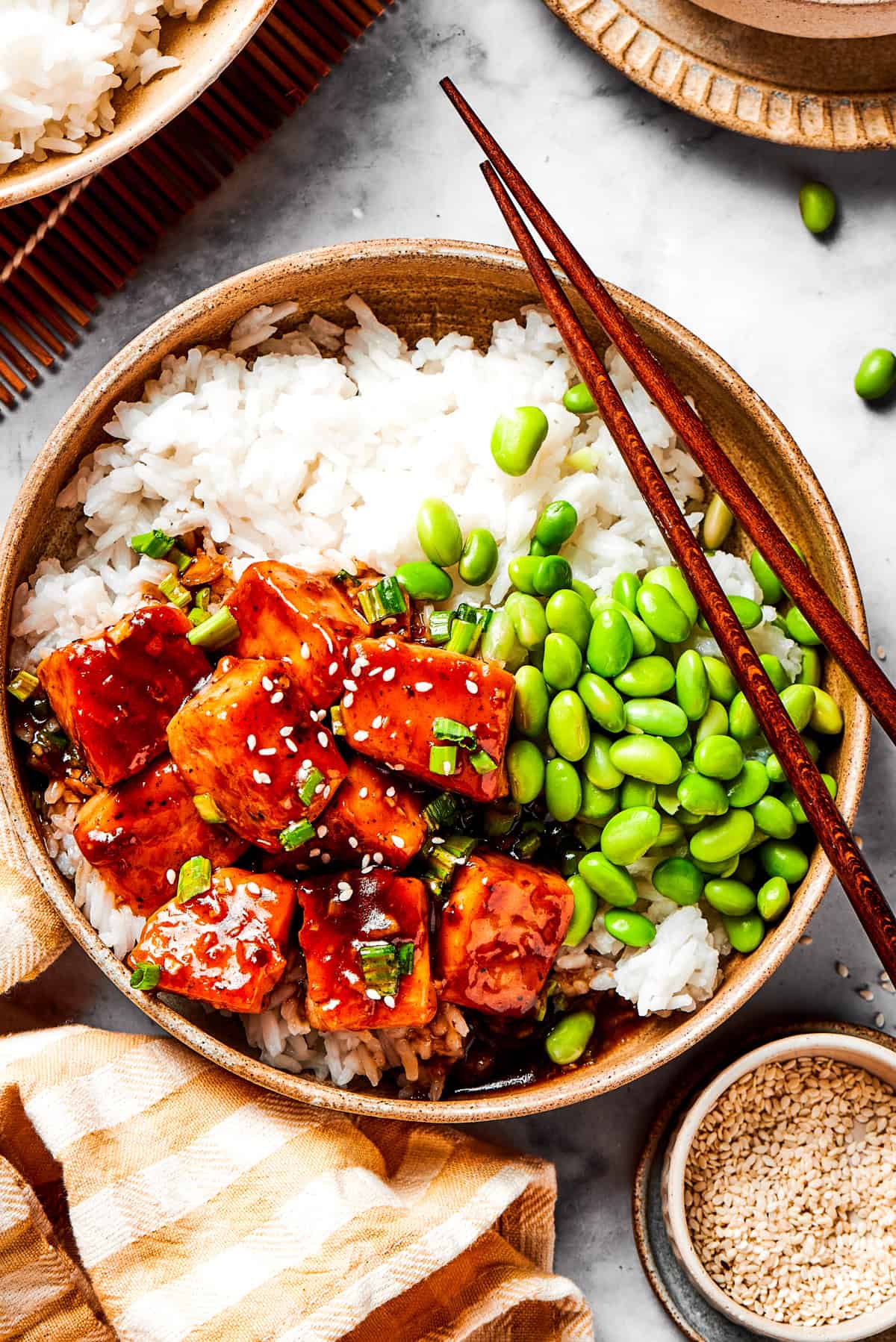 A bowl of white rice topped with cubed salmon and edamame.