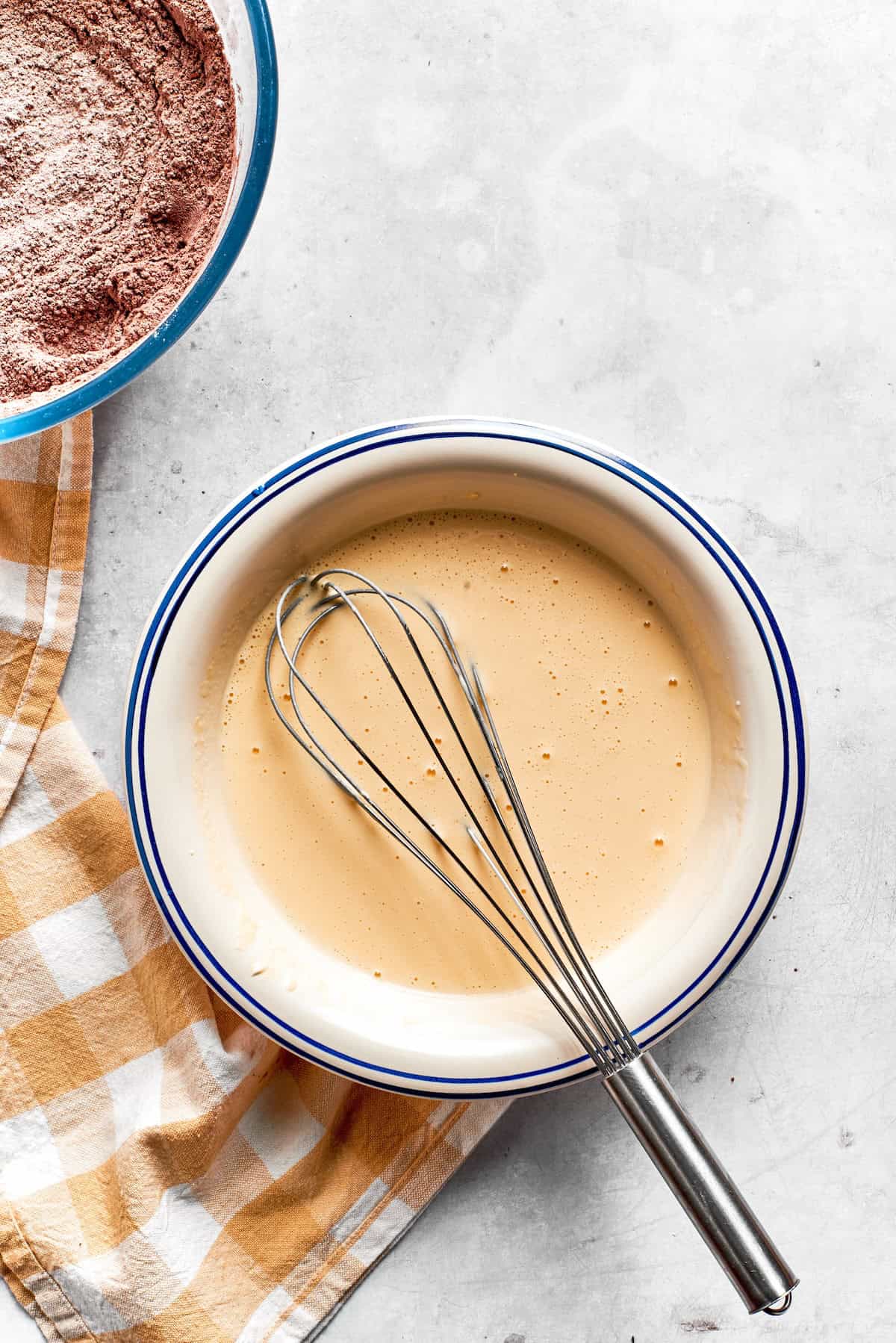 The wet mix for chocolate muffins in a bowl with a whisk.