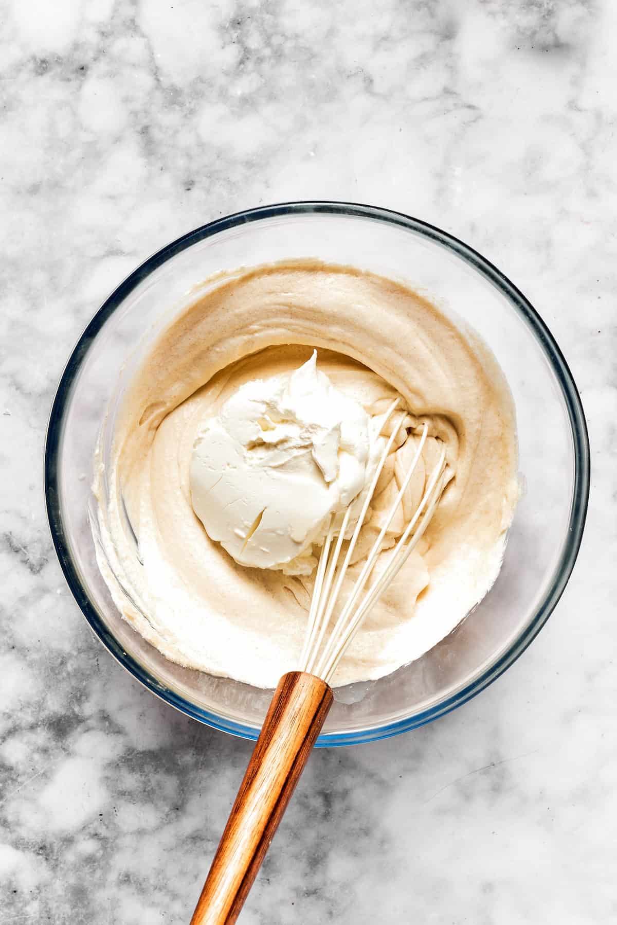 Creamy cheesecake batter is whisked together in a bowl.