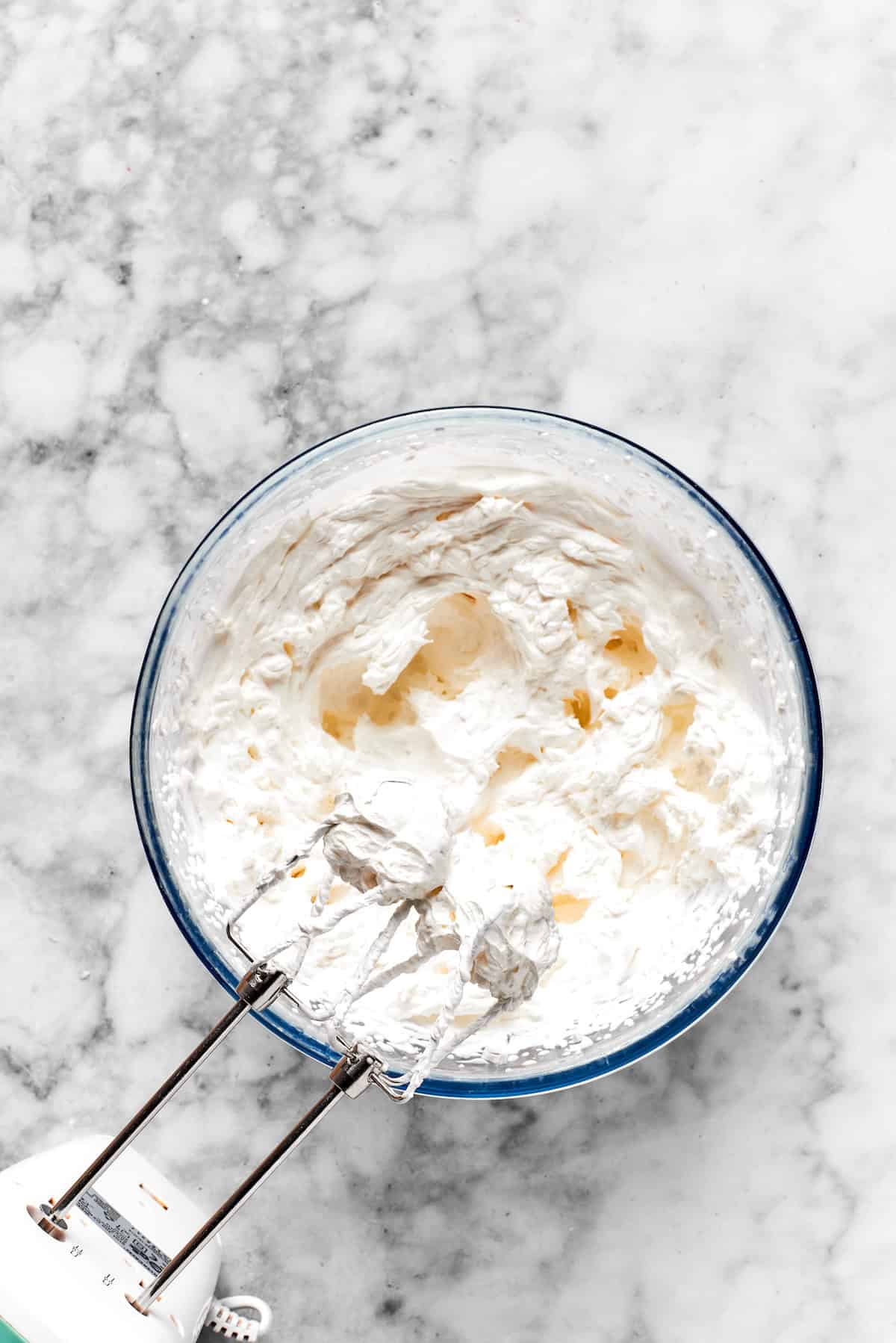 A mixer beats frosting ingredients together in a bowl.