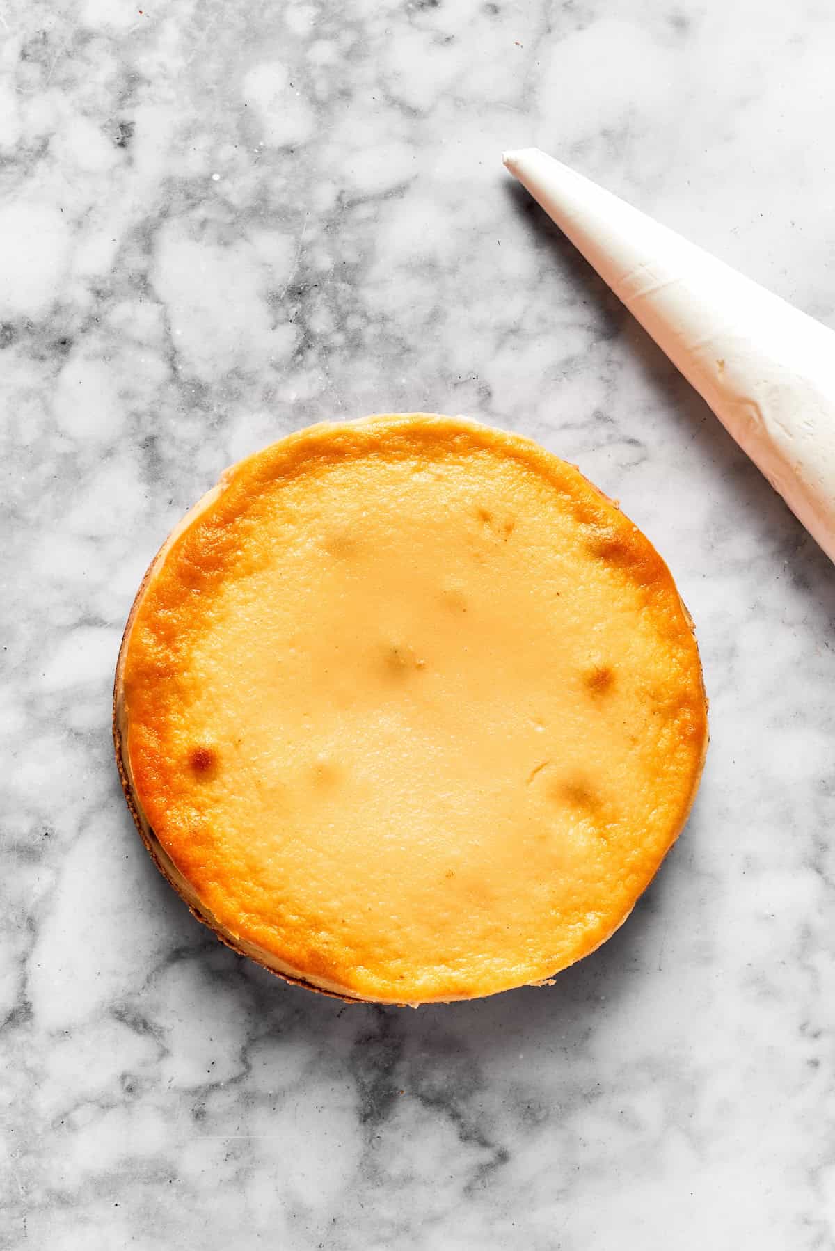 A baked cinnamon roll cheesecake with a piping bag next to it.