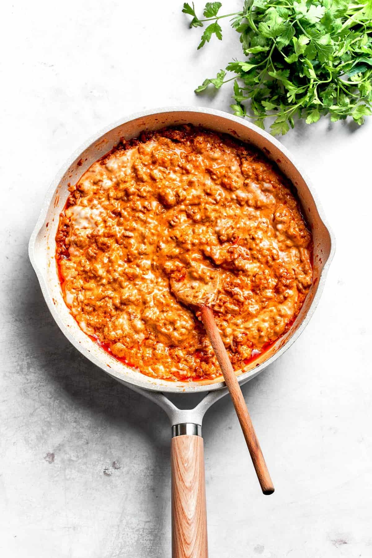 Dorito casserole filling in a skillet with a spoon.