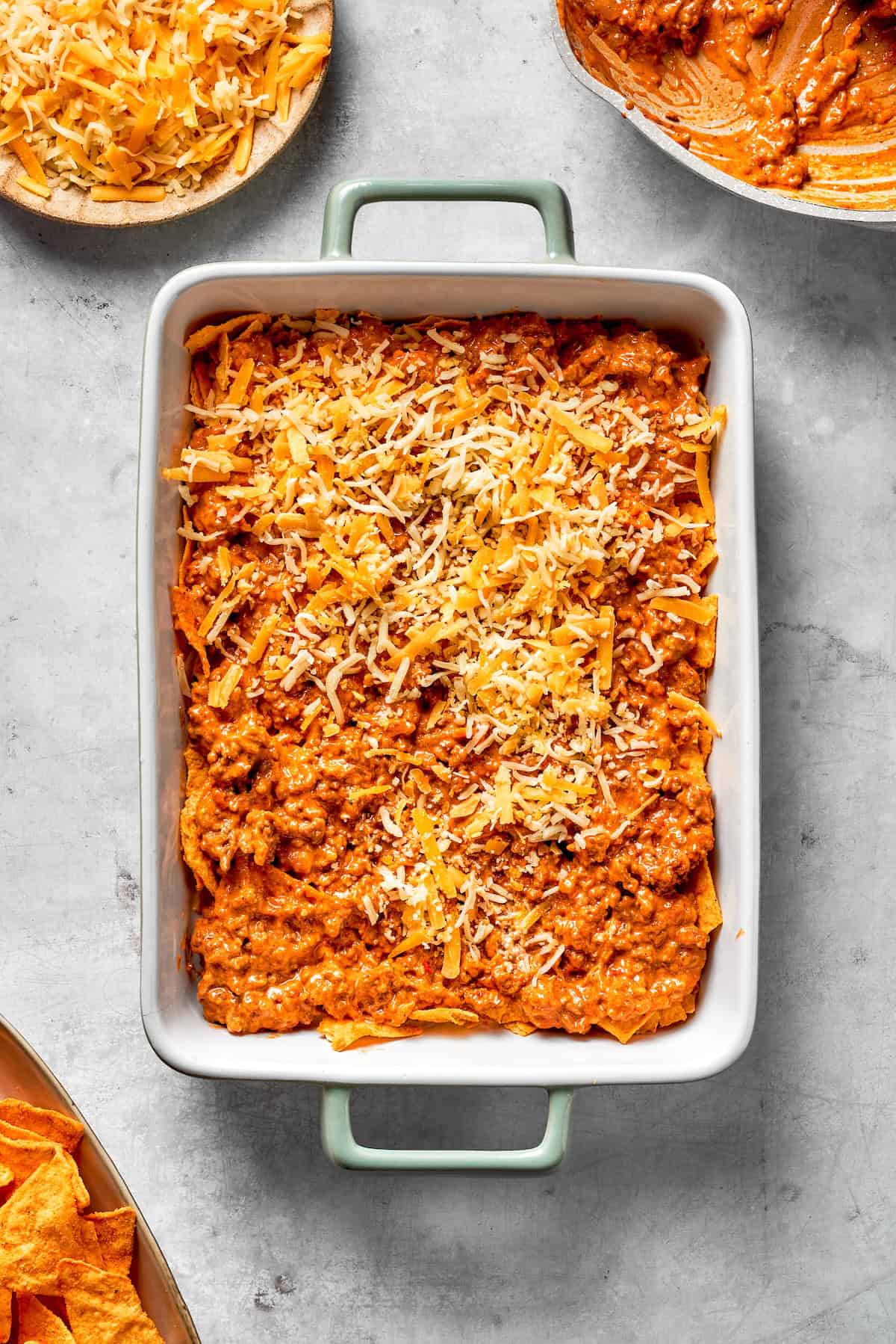 Shredded cheese in added to a Dorito casserole.