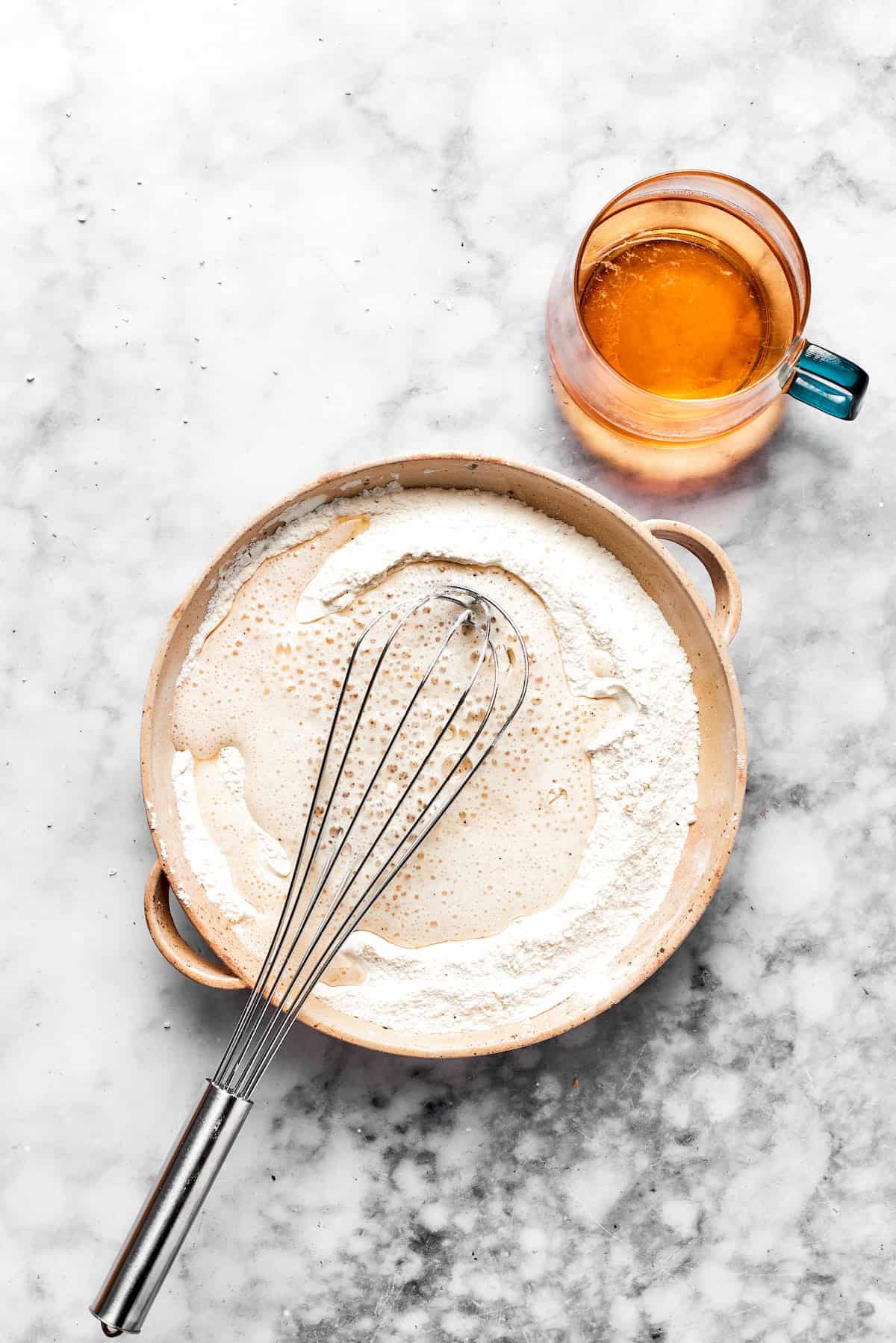 A whisk stirs a bowl of beer batter.