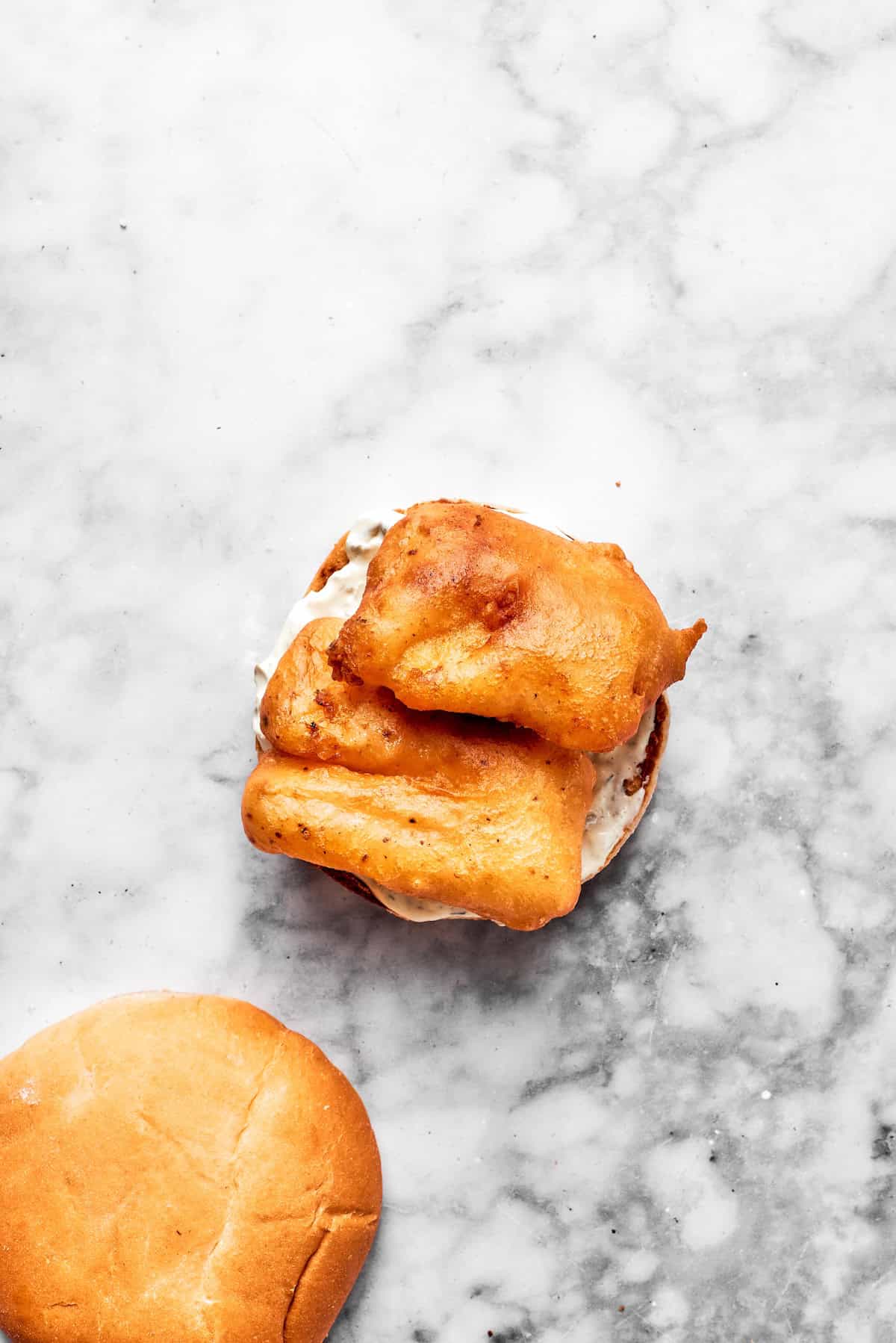 Fried fish pieces are placed on a toasted bun.