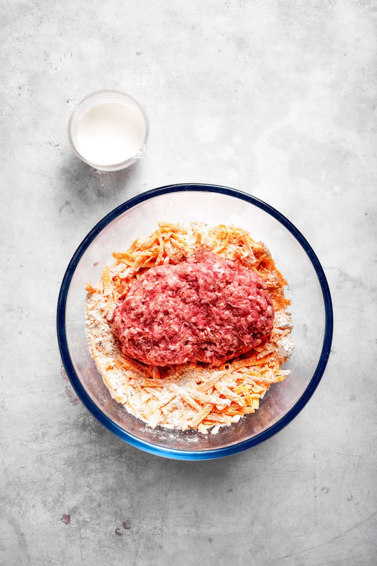 The ingredients for sausage balls placed in a glass bowl.