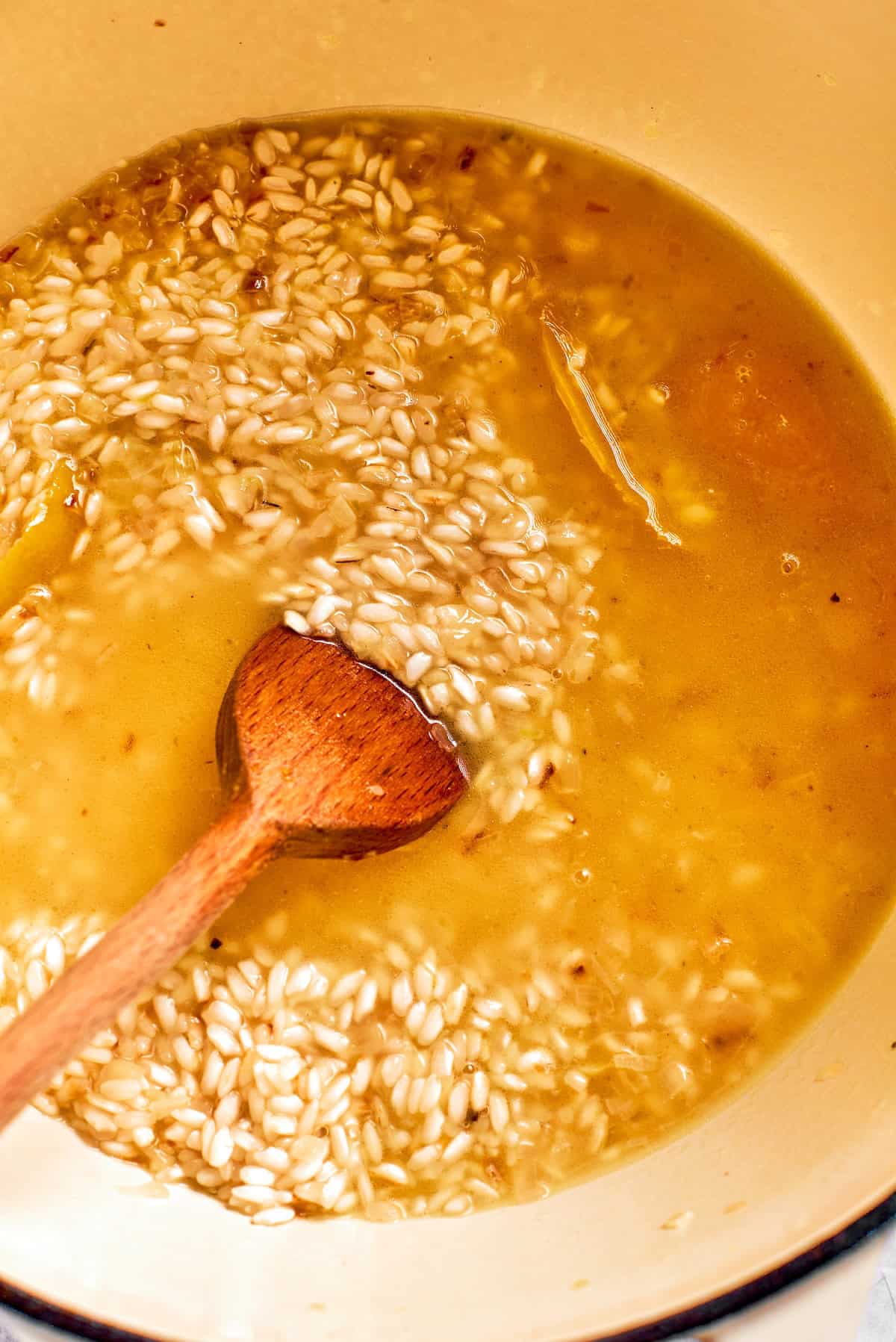 Broth is stirred into risotto rice.