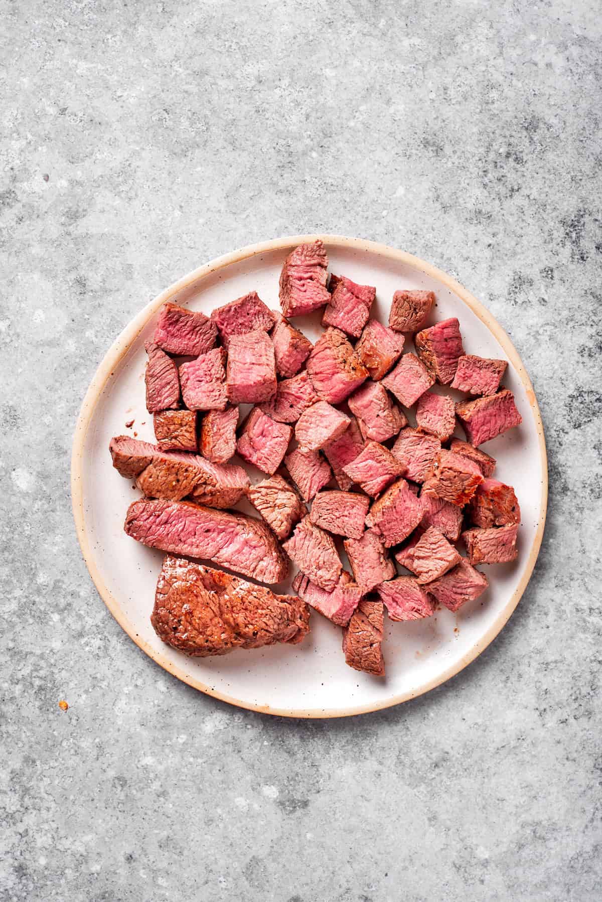 Pieces of cooked steak on a plate.