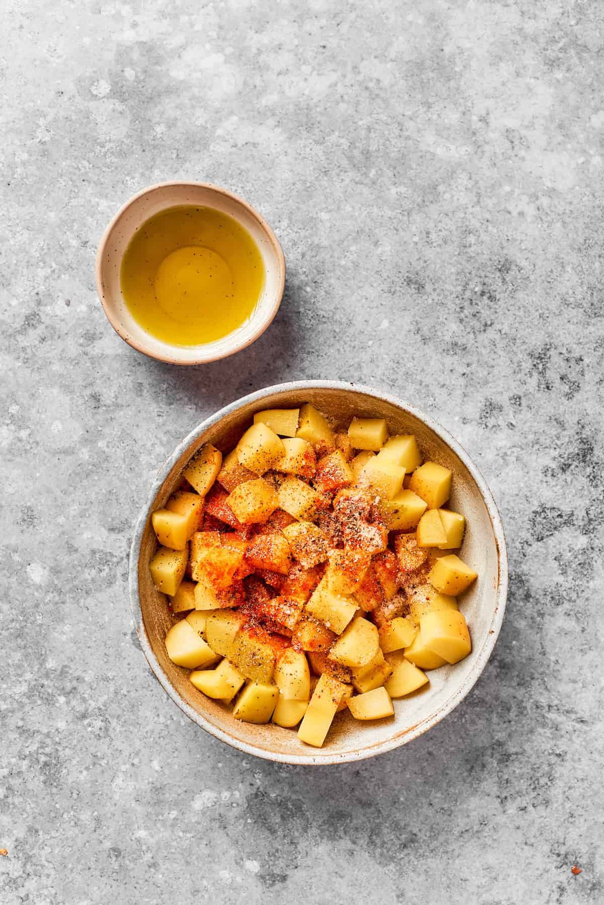 Yellow potato pieces are seasoned in a bowl.