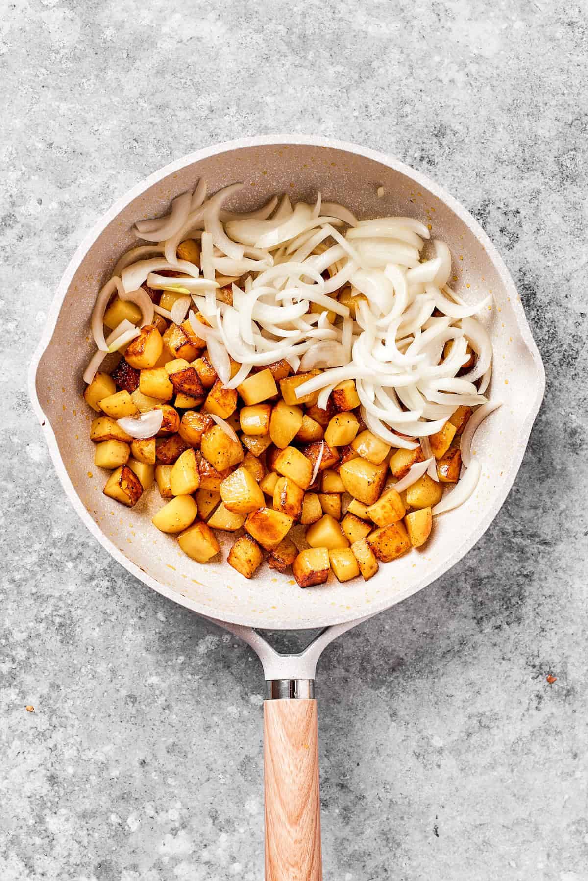 Potatoes and sliced onions in a skillet.