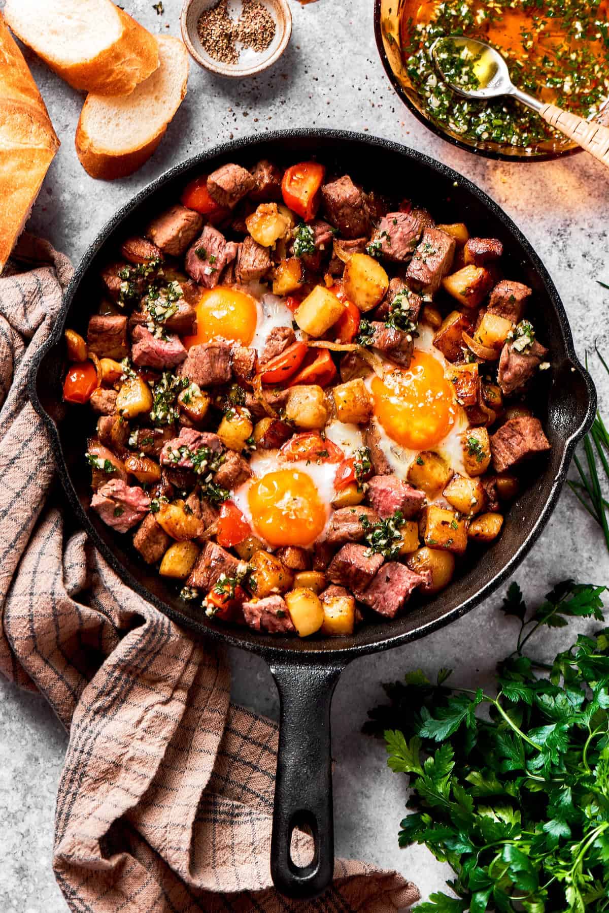 Fried eggs top a skillet of steak and eggs.