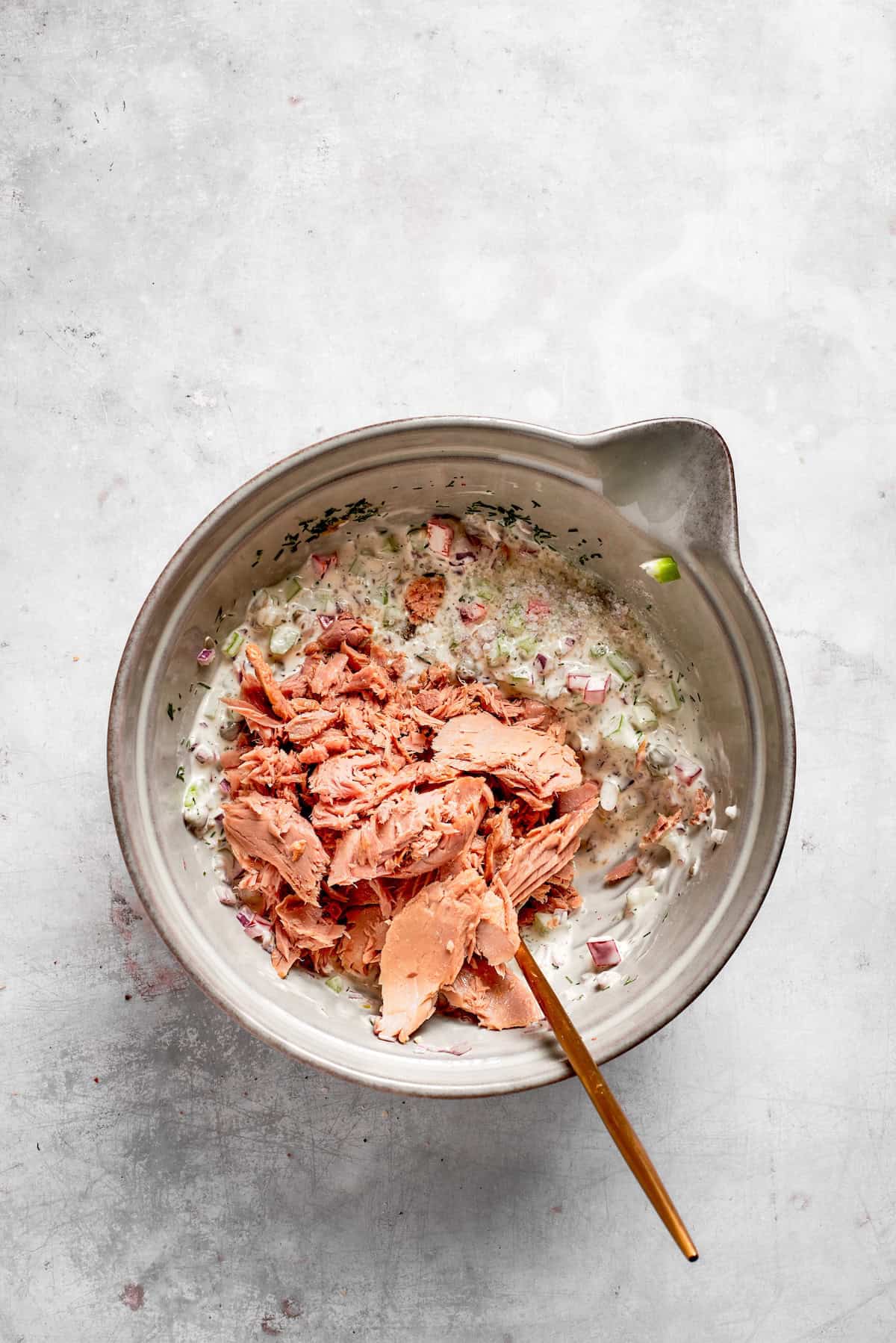 Tuna is added to tuna melt filling in a bowl.