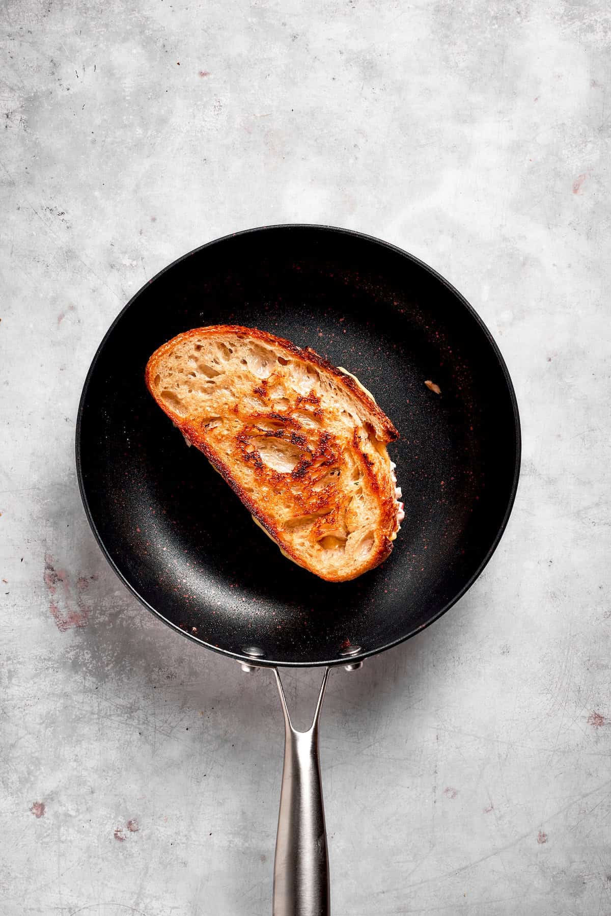 A tuna melt sandwich toasts in a pan.