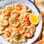 Shrimp risotto served on a plate with a wedge of lemon to the side.