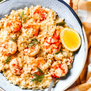 Shrimp risotto served on a plate with a wedge of lemon to the side.