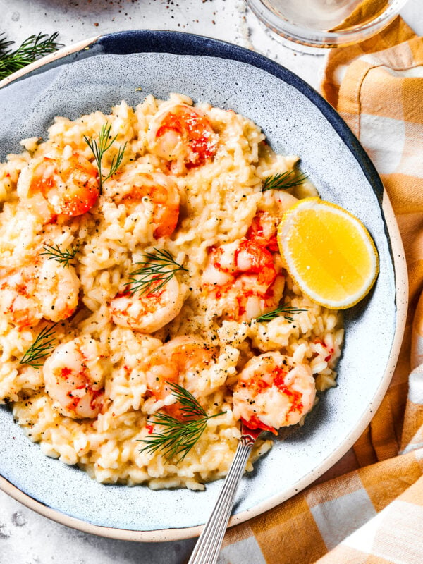 Shrimp risotto served on a plate with a wedge of lemon to the side.