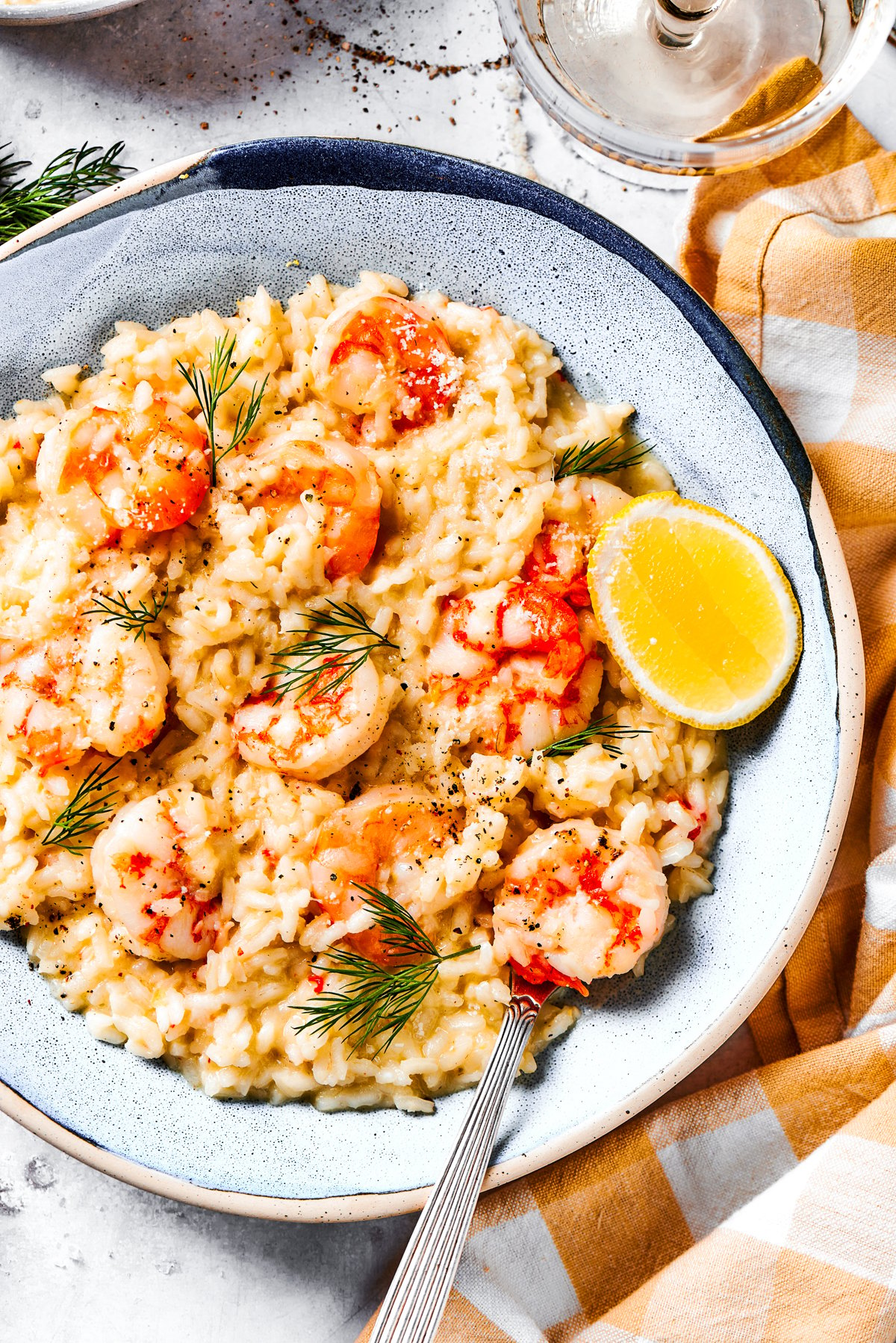 Shrimp risotto served on a plate with a wedge of lemon to the side.