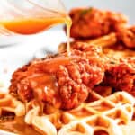 Pouring sauce over waffles and fried chicken.