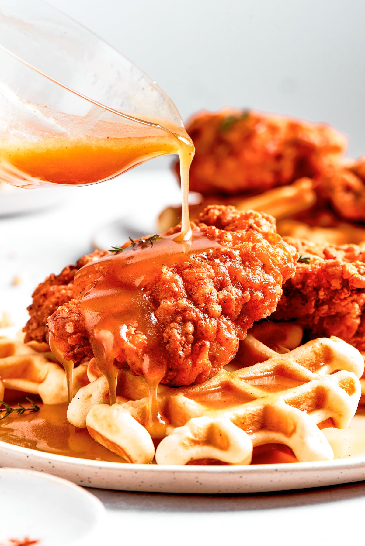 Pouring sauce over waffles and fried chicken.