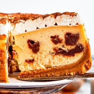 Exposing the cinnamon filling on a slice of a cinnamon roll cheesecake.