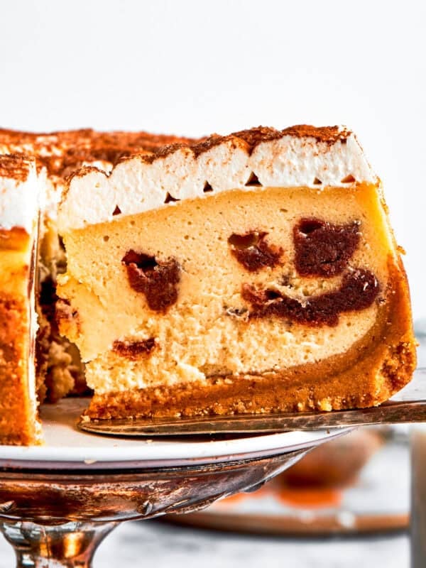 Exposing the cinnamon filling on a slice of a cinnamon roll cheesecake.