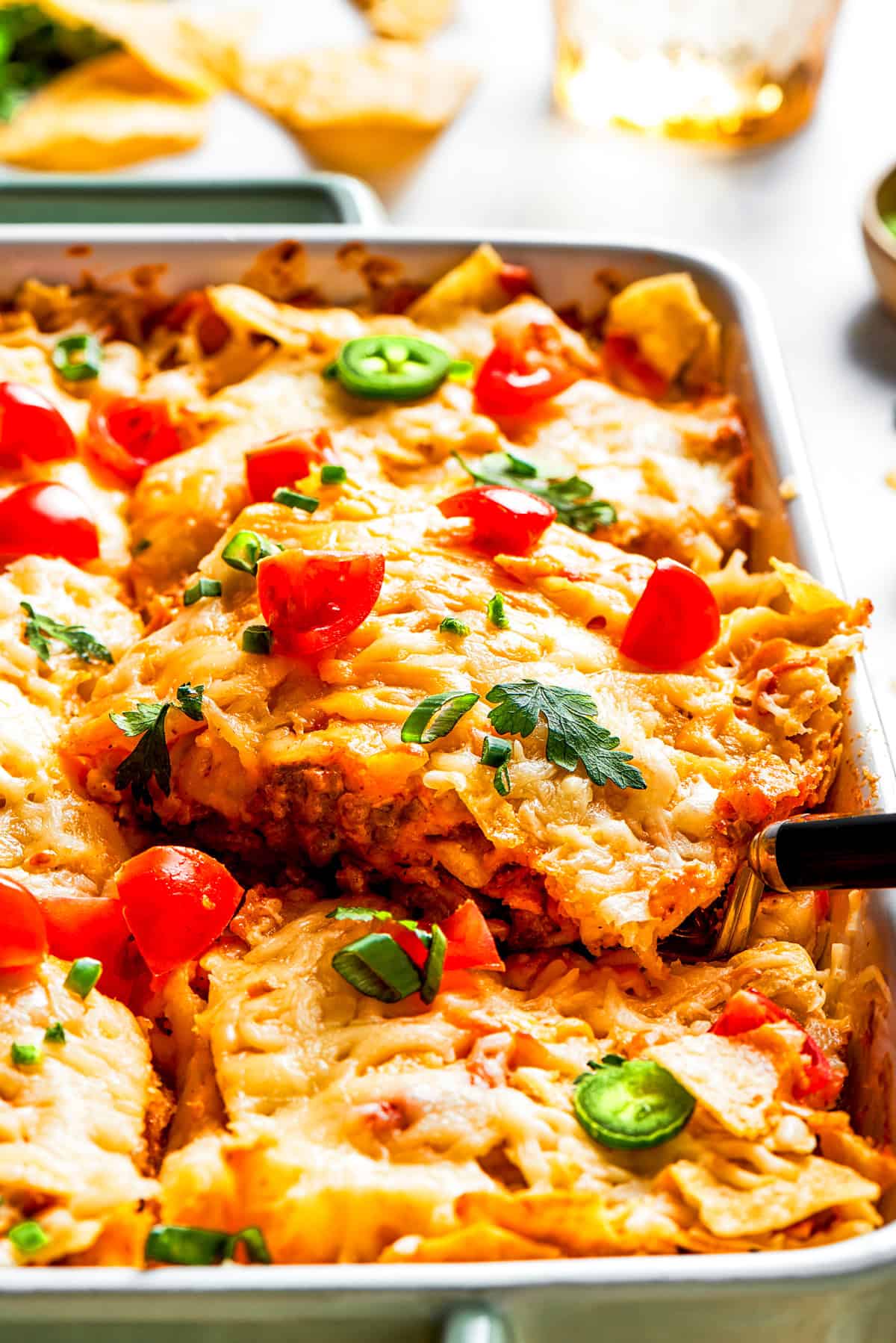 Side shot of a casserole topped with melted cheese, halved cherry tomatoes, and fresh greens.