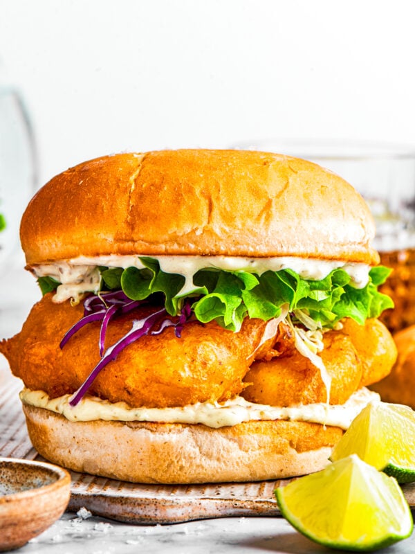 A sandwich with fried fish, lettuce, and tartar sauce.