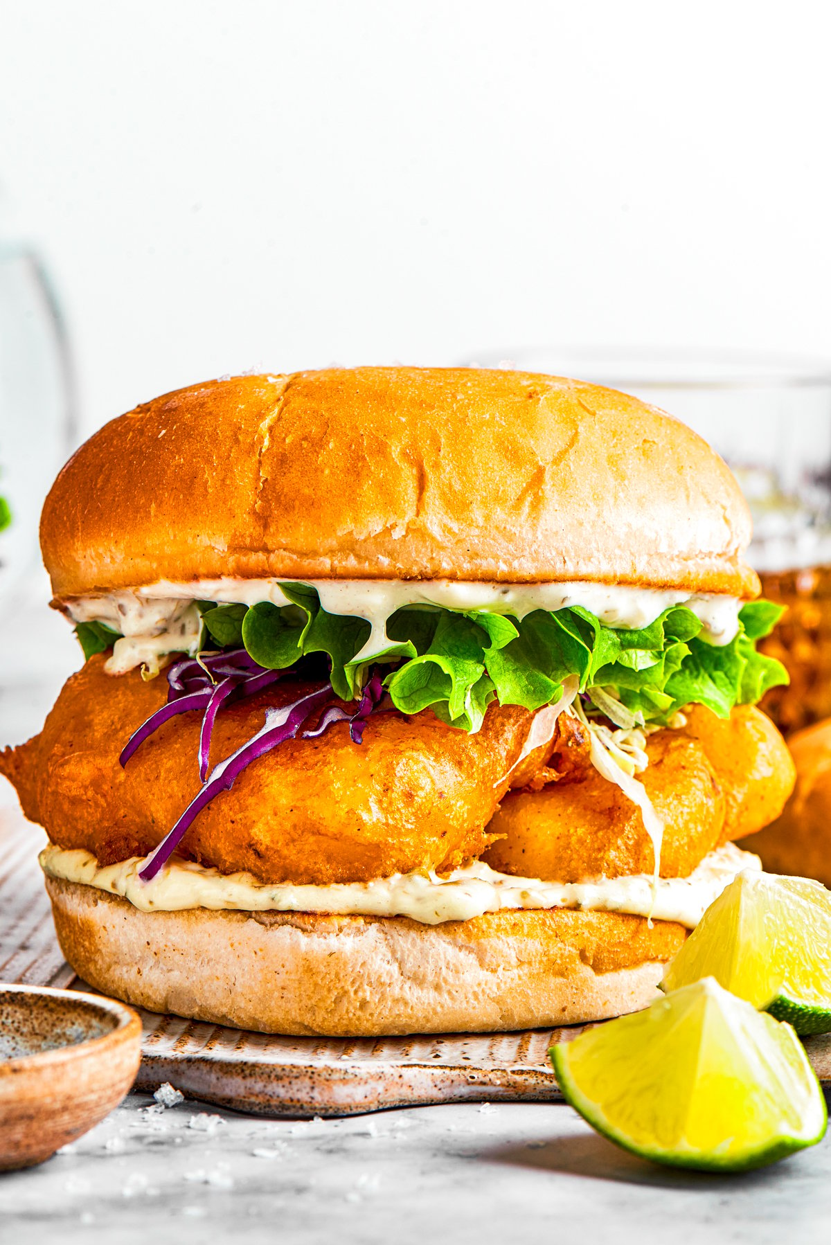 A sandwich with fried fish, lettuce, and tartar sauce.