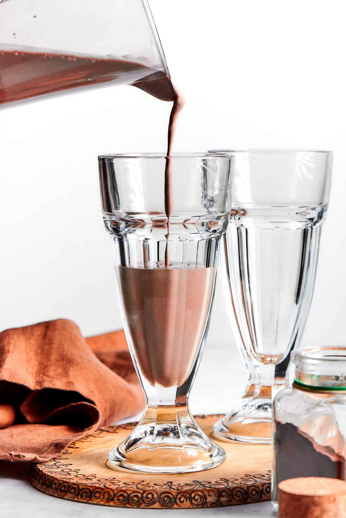 A chocolate milkshake is poured into a glass.