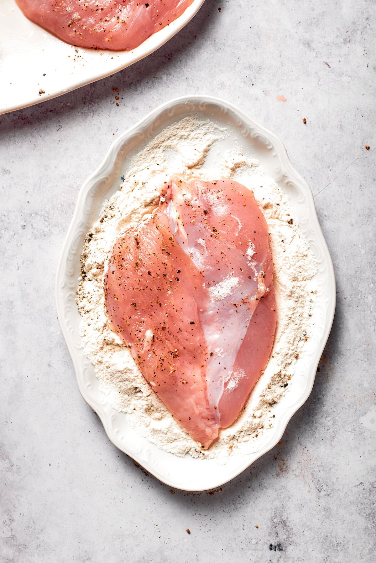Chicken breast is pressed into breadcrumbs.