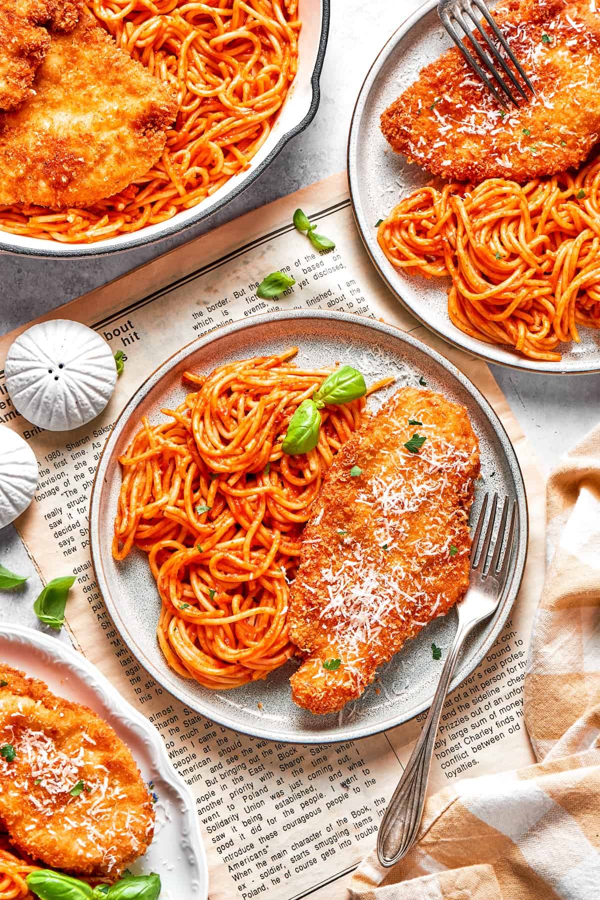 Crusted chicken romano is served on plates with pasta.