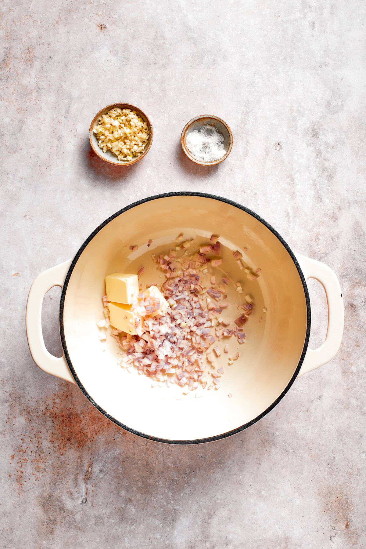 Butter and shallots cook together in a soup pot.