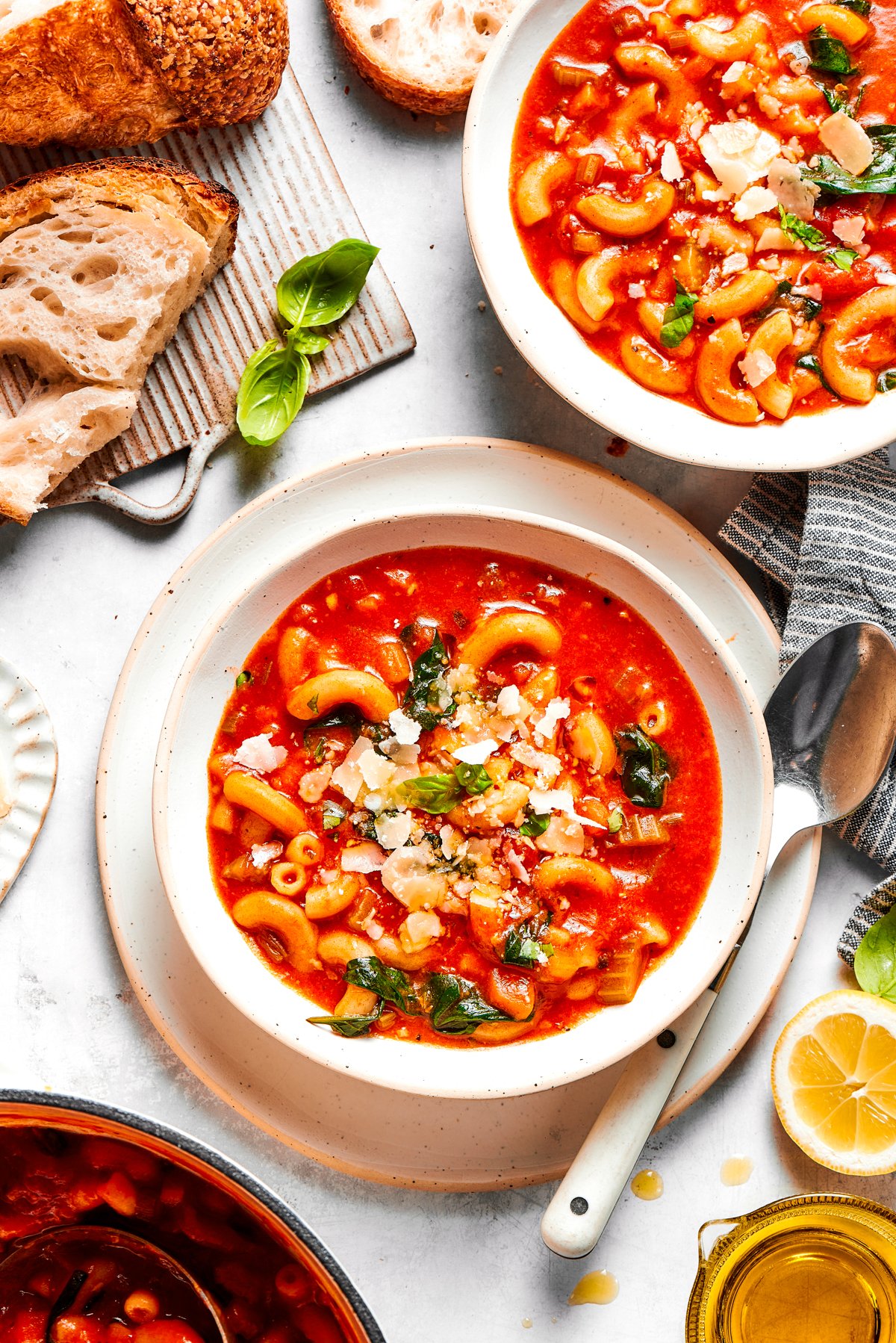 Two bowls of tomato soup, with bread and spoons placed near the bowls.