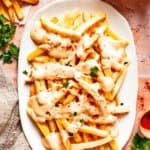 Voodoo fries served on an oval platter and topped with cheese sauce.