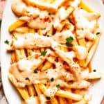 A platter of voodoo fries topped with cheese sauce.