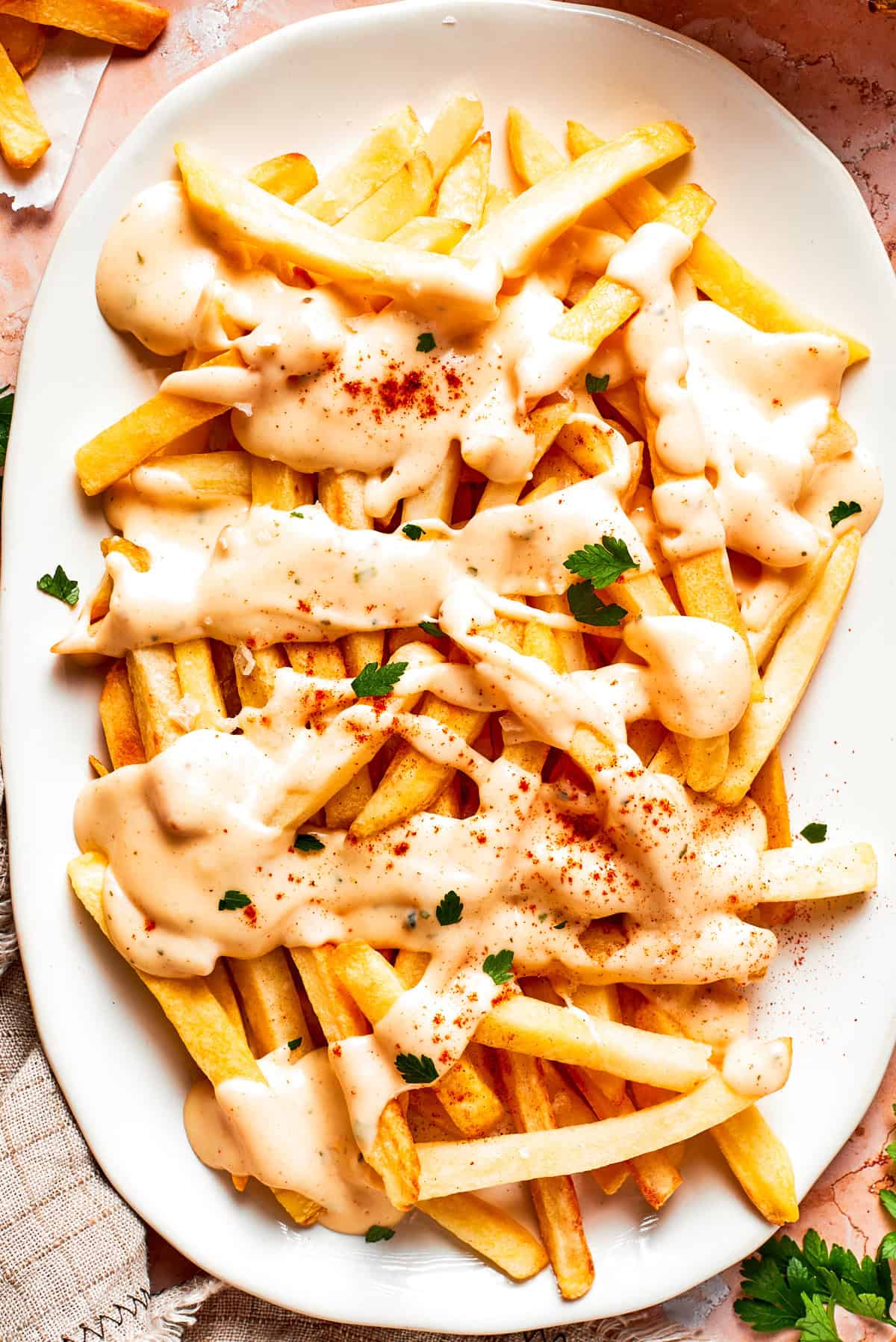 Crispy voodoo fries are smothered in a lightly spiced cheese sauce and served hot and fresh! My version of the popular Wingstop dish. A platter of voodoo fries topped with cheese sauce.