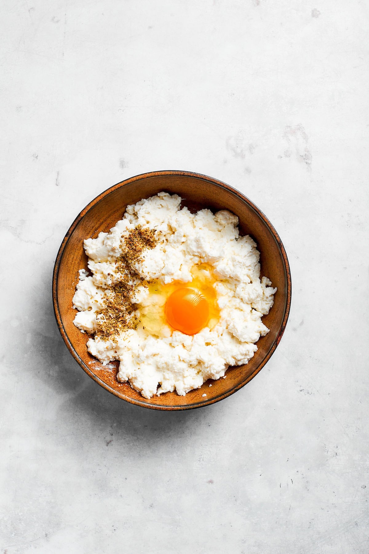 An egg is added to ricotta cheese.