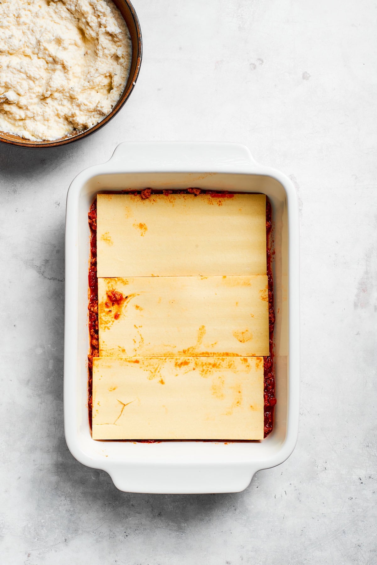 Lasagna sheets are layered in a pan.