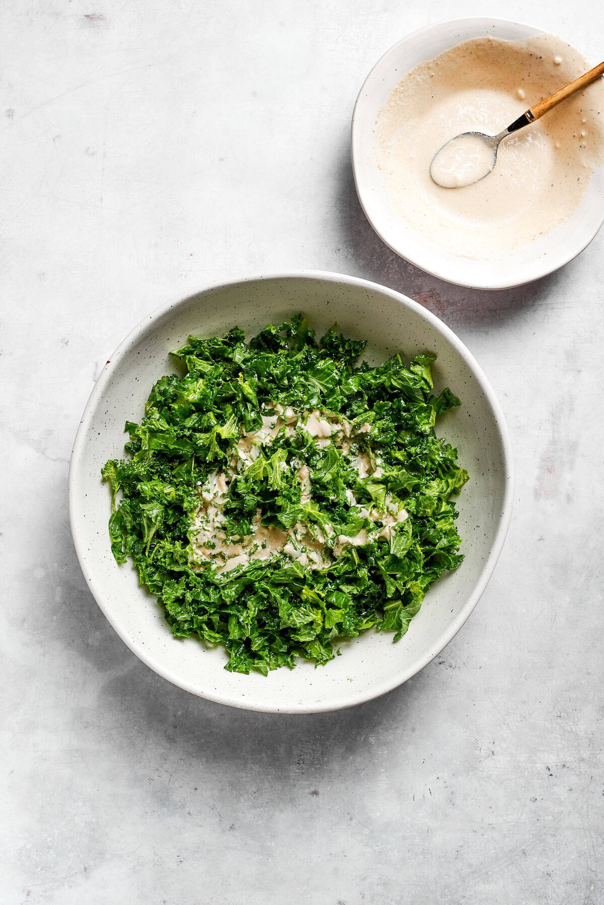 Dressing is added to kale caesar salad.