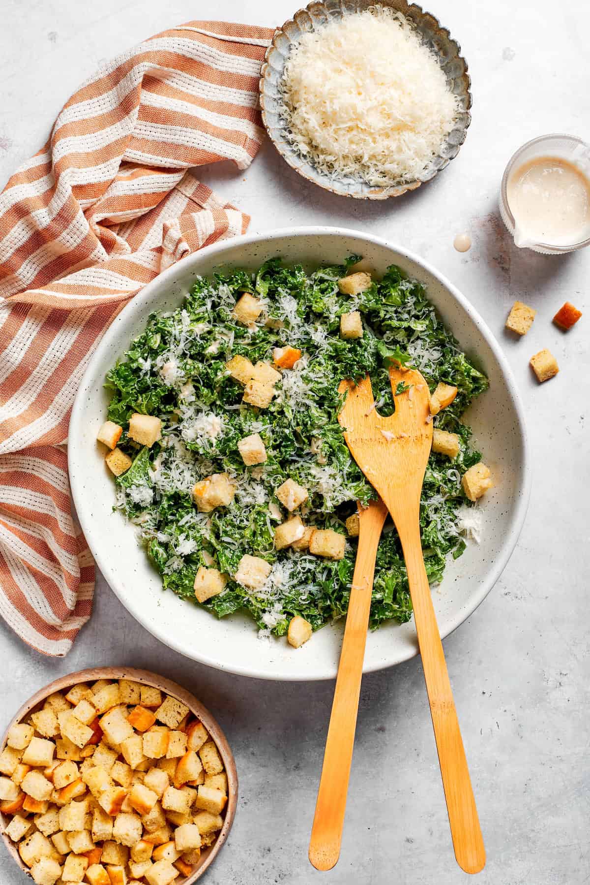 A striped napkin next to a bowl of kale caesar salad.