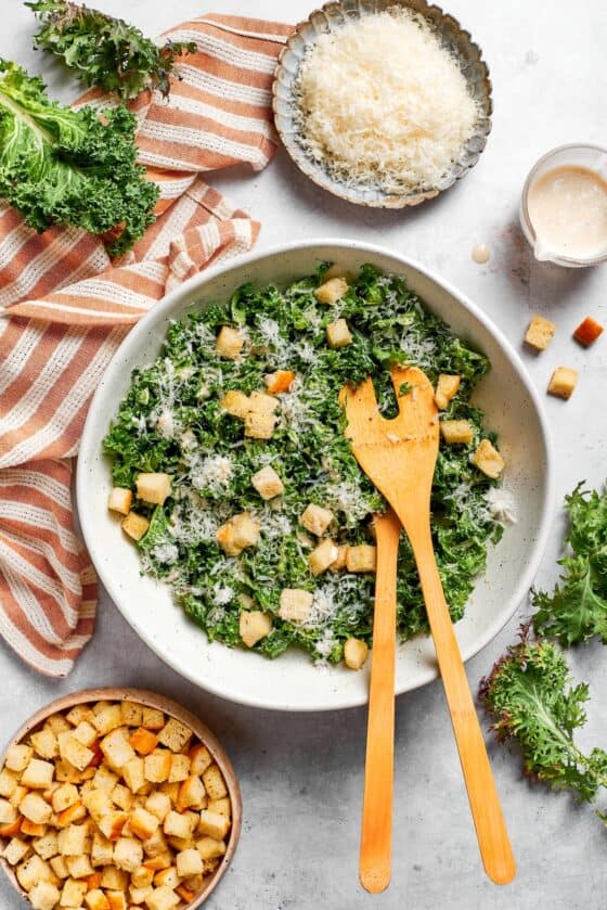 Bowls of cheese and croutons next to a bowl of kale salad.