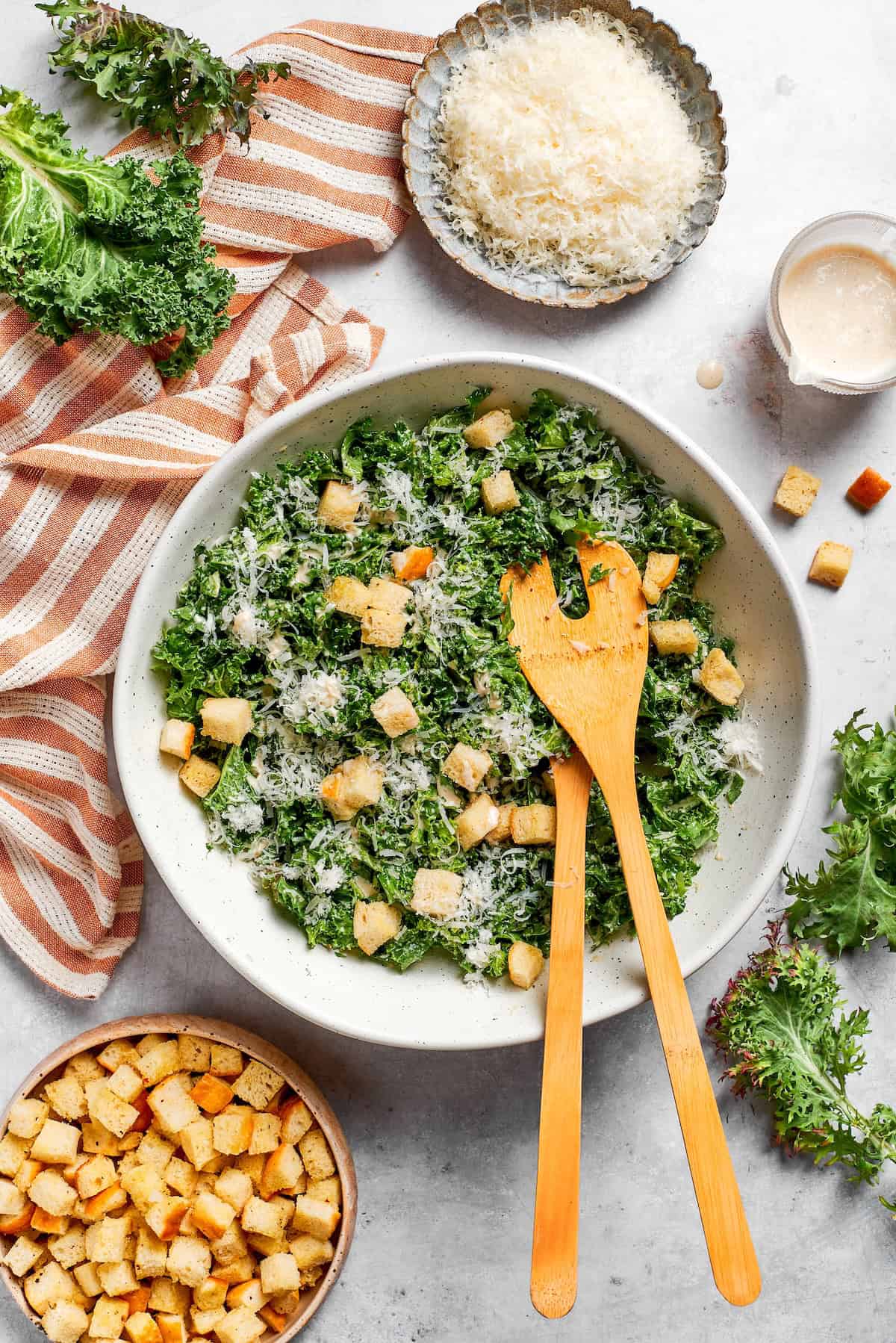 Bowls of cheese and croutons next to a bowl of kale salad.
