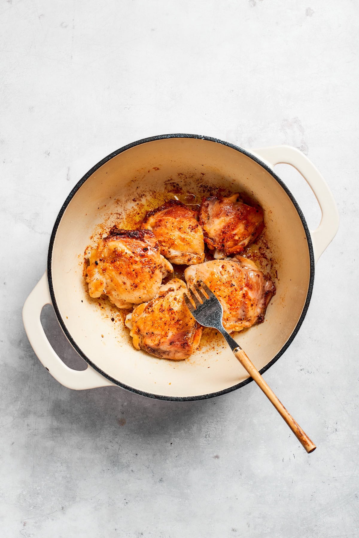 A fork moves chicken in a pot.