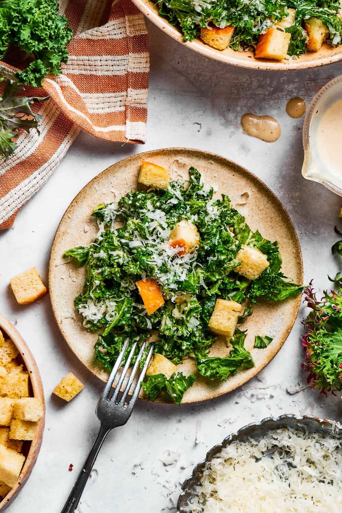 A plate of kale Caesar salad topped with croutons and grated cheese.