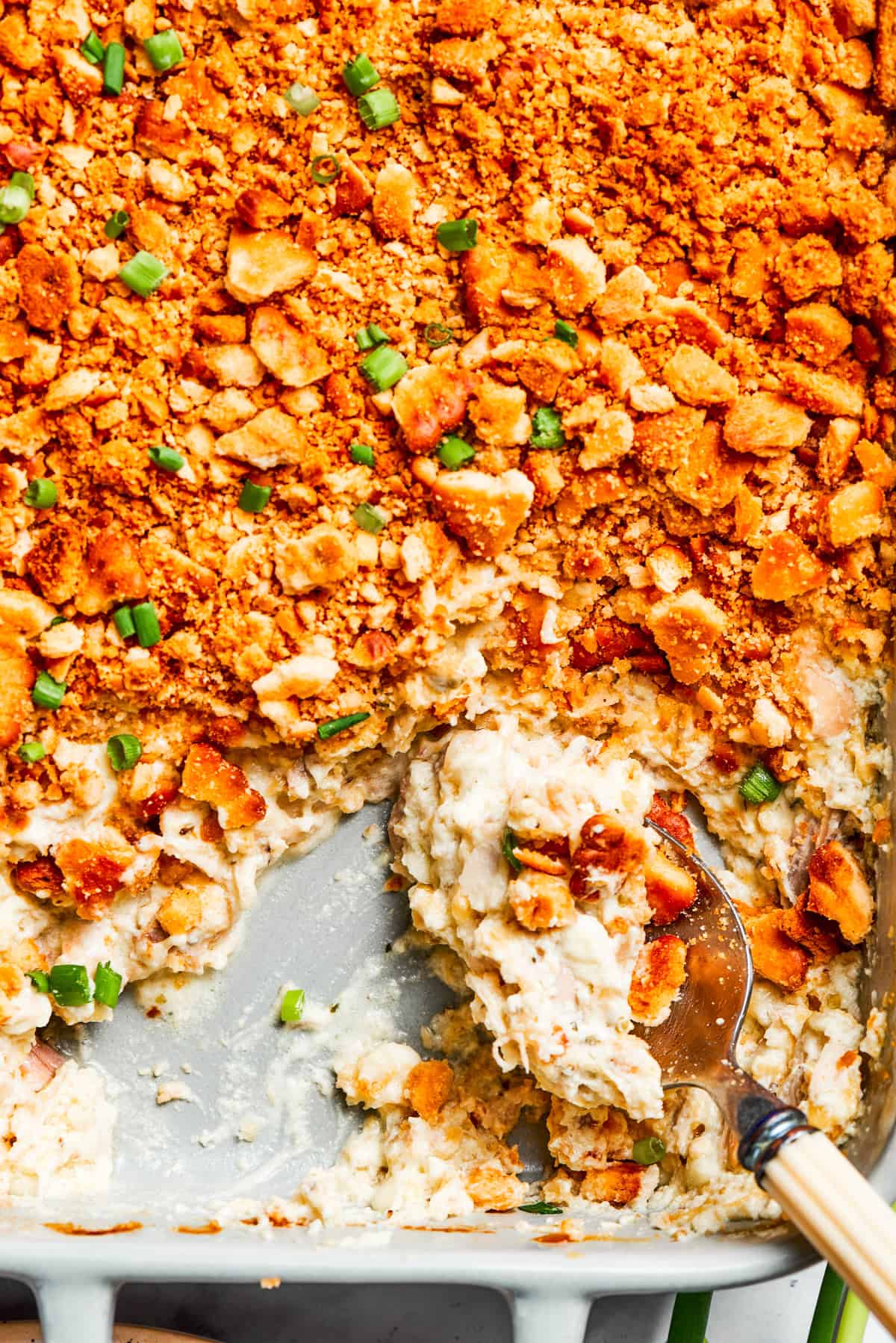 A serving spoon scoops into million dollar chicken casserole.