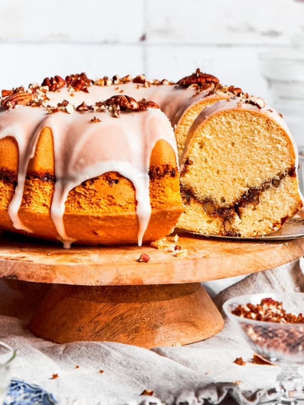 Sock it to me, cake served on a tall cake plate with a slice cut out exposing the cinnamon sugar ribbon that goes through the cake.