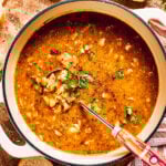 A pot of spicy chicken soup is mixed to combine all the ingredients.
